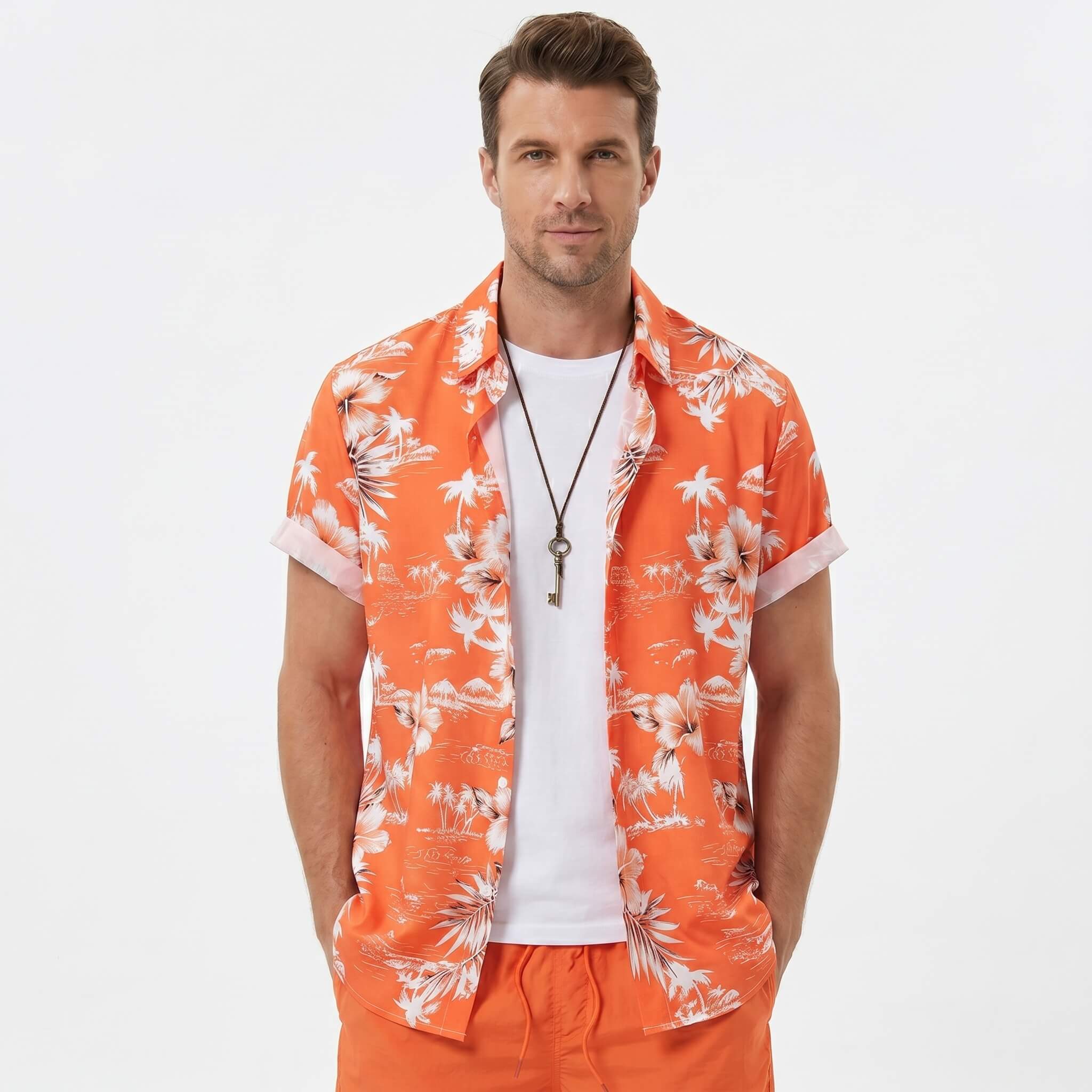 Man in white palm tree tropical print shirt and swim shorts walking along a sunny beach setting
