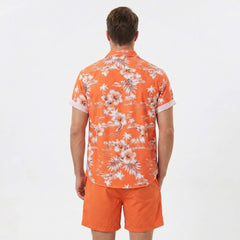 Full length view of man wearing white palm tree tropical print shirt and swim shorts on plain background
