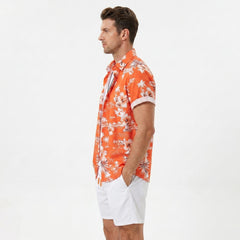 Man wearing white palm tree tropical print shirt and swim shorts walking in sunny outdoor setting