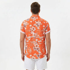 Side view of man in white palm tree tropical print button up shirt and swim shorts on plain background
