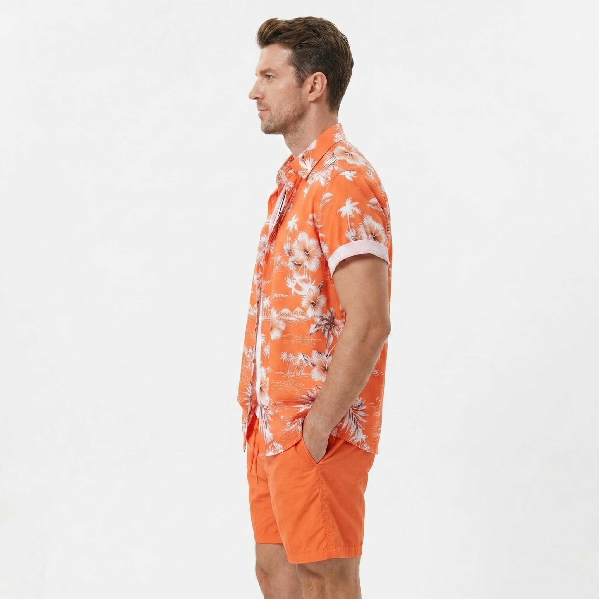 Three quarter view of man wearing white palm tree tropical print shirt and swim shorts outdoors