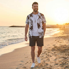 Man wearing white palm trees print button up shirt and striped swim shorts in beach lifestyle setting