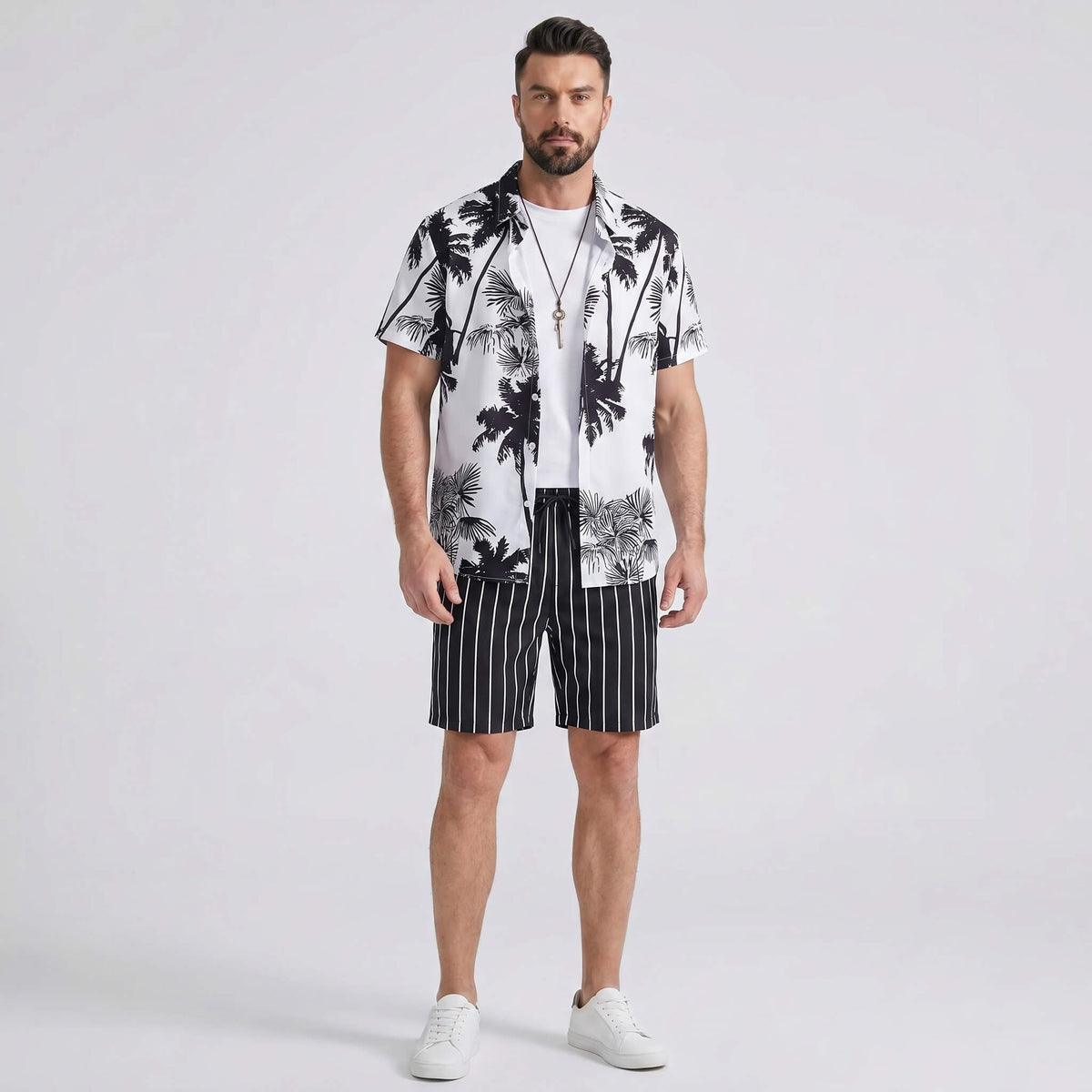 Man wearing a white palm trees print button up shirt and striped swim shorts front view on plain background