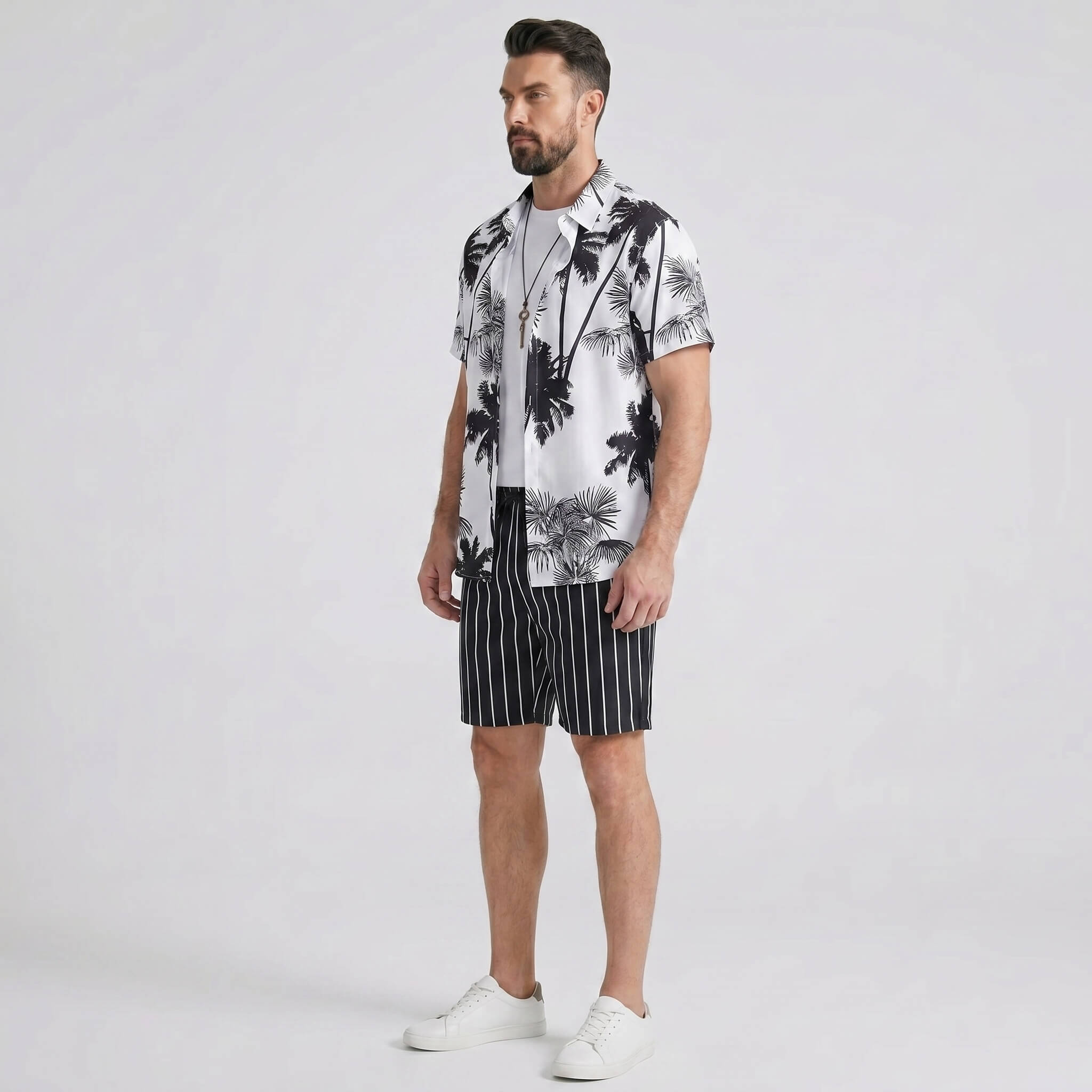 Side view of man in white palm trees print button up shirt and striped swim shorts on plain background