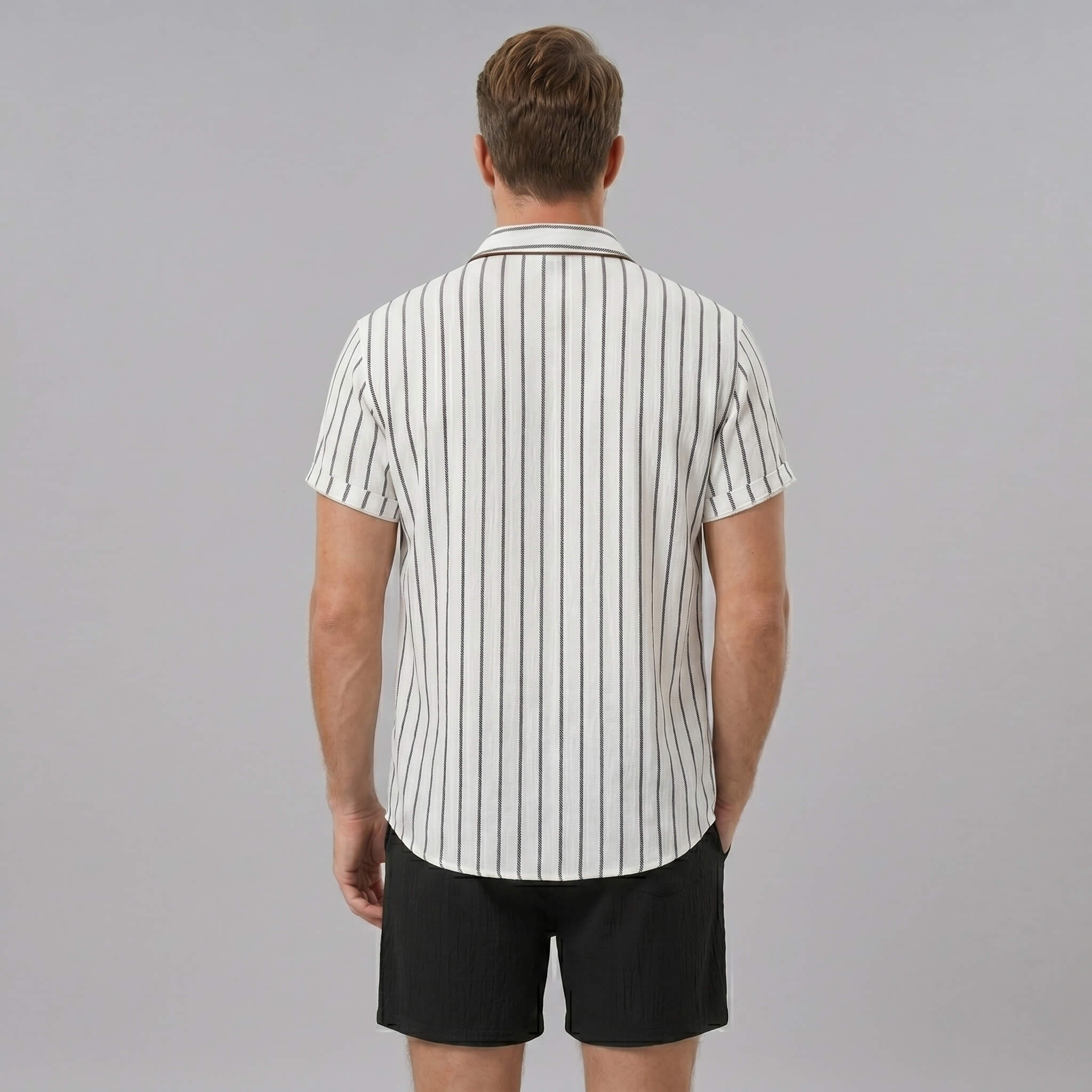 Side view of man in white striped cotton blend button up shirt and crinkle textured drawstring shorts