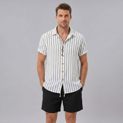 Man wearing a white striped shirt and black shorts on a gray background