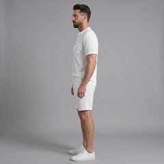 Side view of man in white waffle stand collar shirt and drawstring shorts on plain background