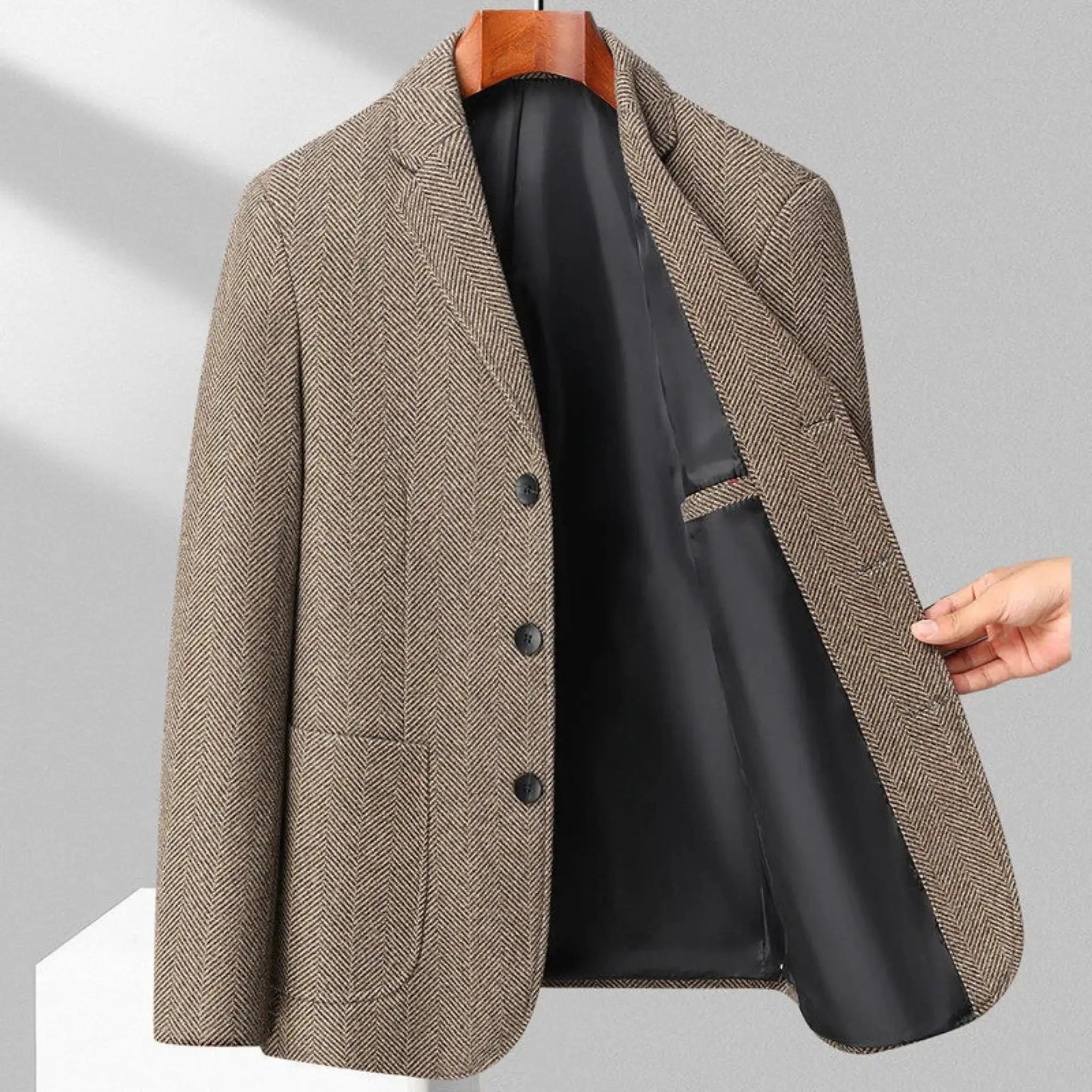 MannerCo khaki woolen blazer shown open to reveal black lining hung on wooden hanger